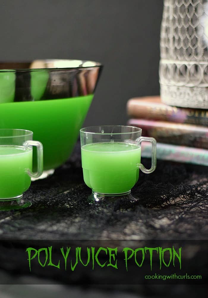 Polyjuice Potion Cocktail in a large punch bowl and in two small clear mugs with a stack of books and a bird cage in the background