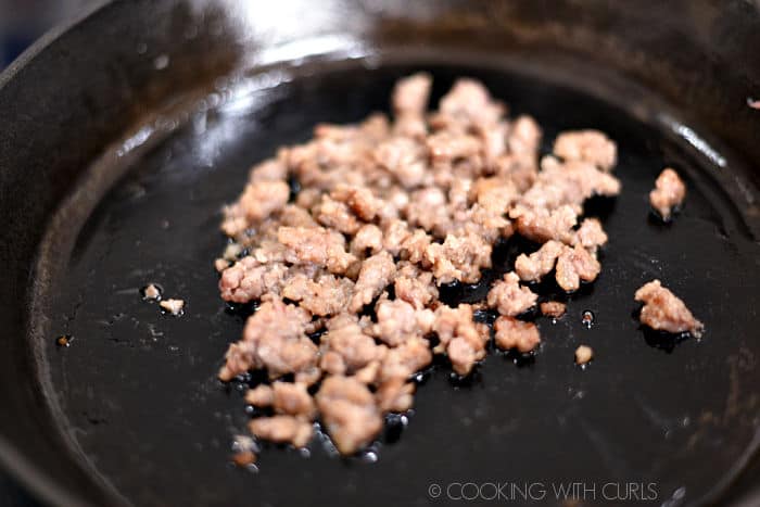 pork sausage cooking in a cast iron skillet. 