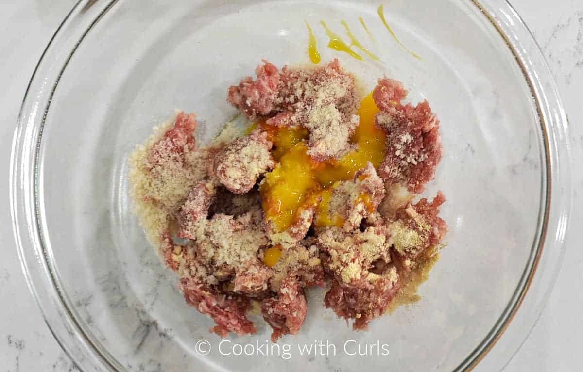 Pork sausage, panko crumbs, seasoning, and egg in a mixing bowl. 