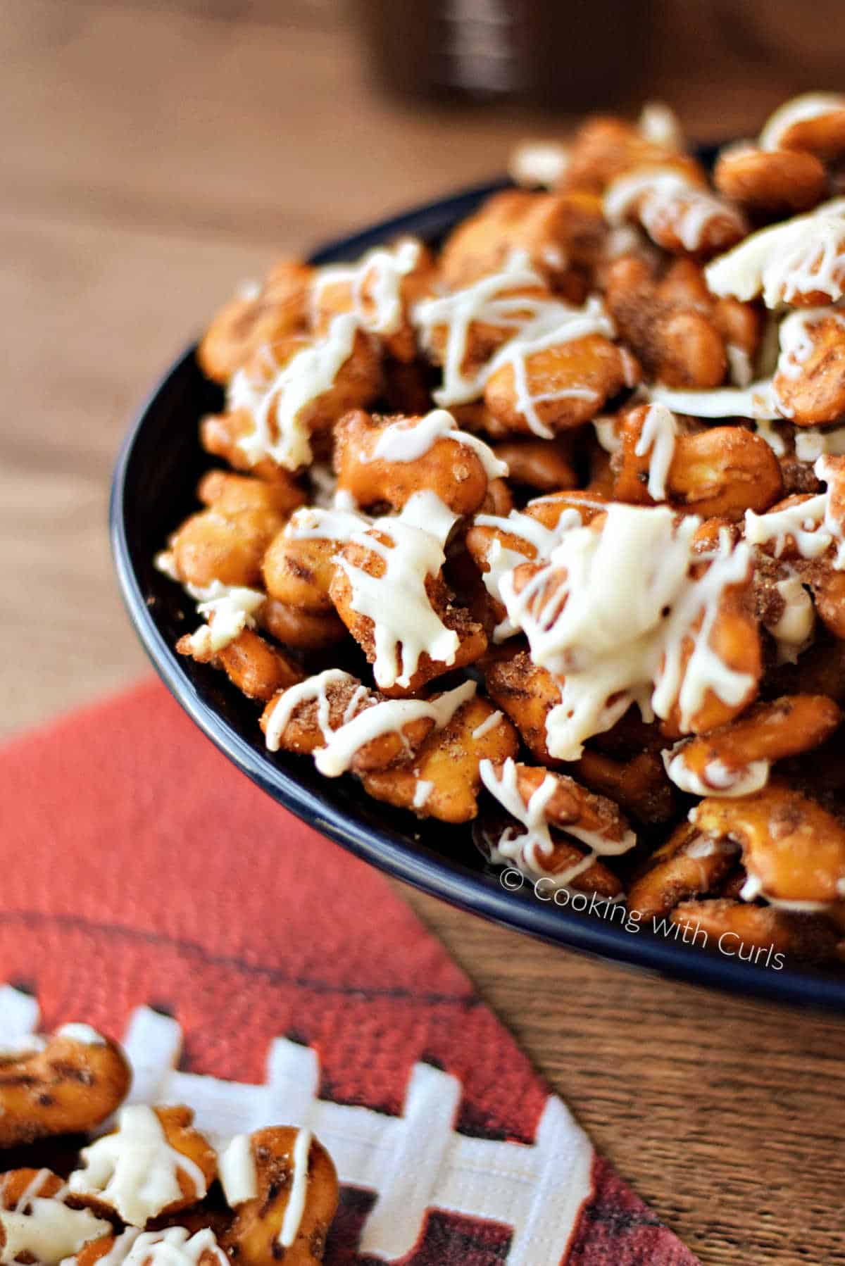 Pretzel Goldfish crackers mixed with cinnamon sugar and drizzled with white chocolate in a bowl next to a football napkin. 