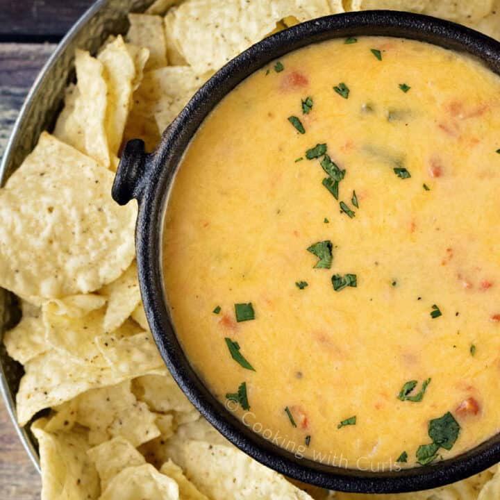 Queso Dip in a black cast iron bowl surrounded by tortilla chips.