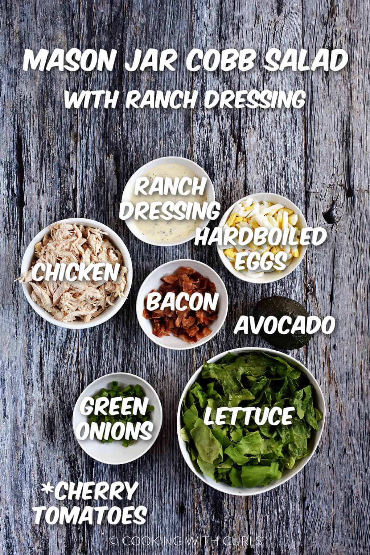 Ranch dressing, hardboiled eggs, avocado, bacon, chicken, green onions, and lettuce in white bowls and cherry tomatoes listed. 