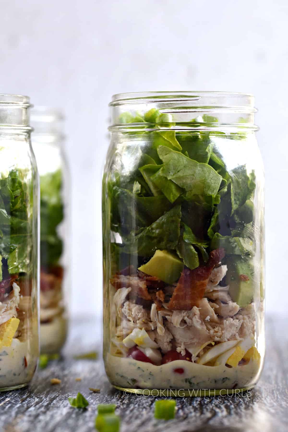 Ranch dressing, tomato, egg, bacon, avocado, and lettuce layered in a Mason jar. 