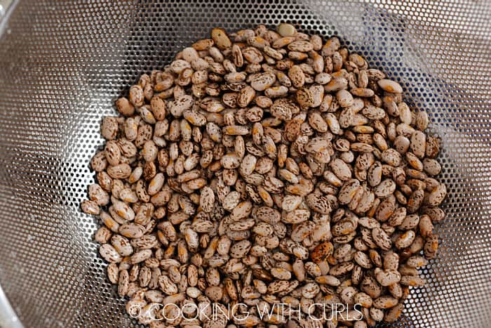 Rinsed, dry pinto beans in a metal colander. 