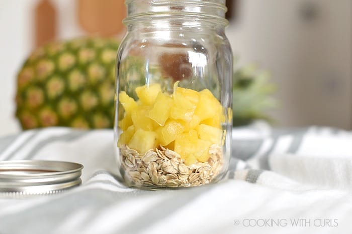 Rolled oats and fresh pineapple chunks in a glass mason jar. 