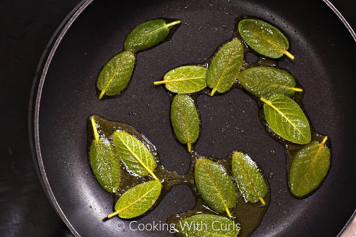 Sage leaves simmering in a small skillet with olive oil. 