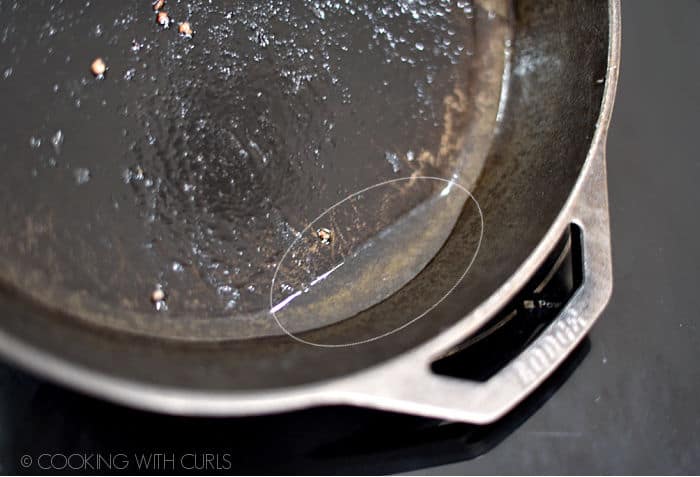 sausage grease collected at the bottom of a tilted cast iron skillet. 