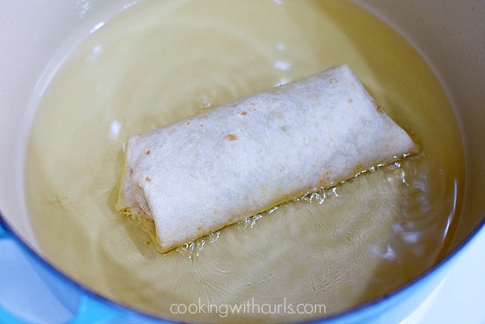 Beef Chimichangas frying in hot oil inside a large Dutch oven. 