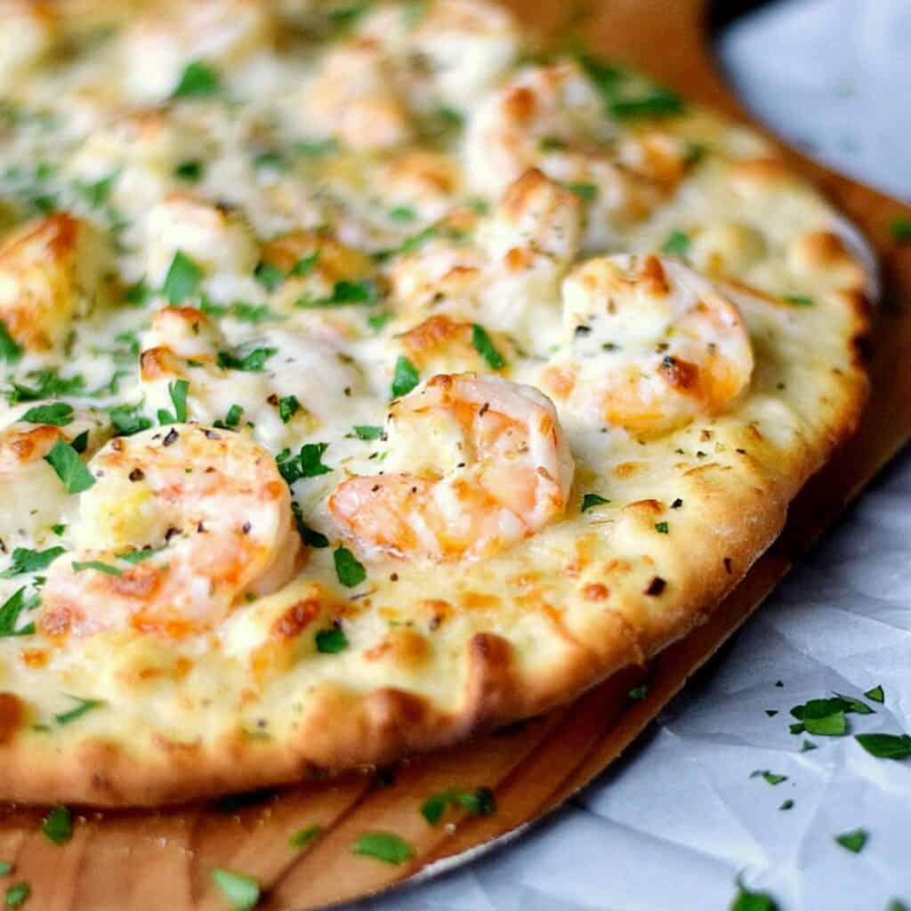 shrimp scampi pizza on a wood pizza peel.