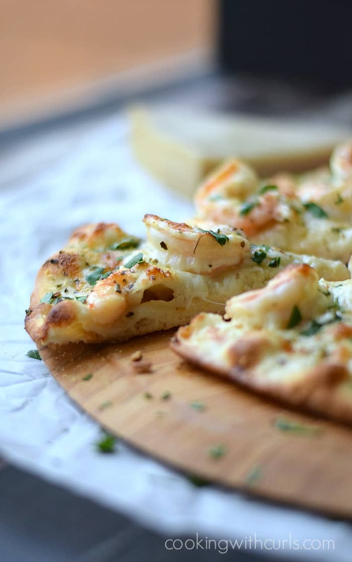 A slice of Shrimp Scampi Pizza with puffy Homemade Crust.