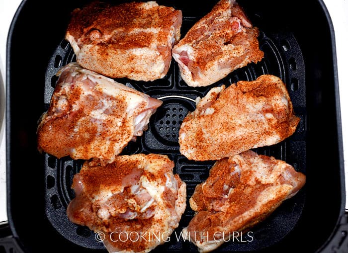 Six chicken thighs skin side down in an air fryer basket. 