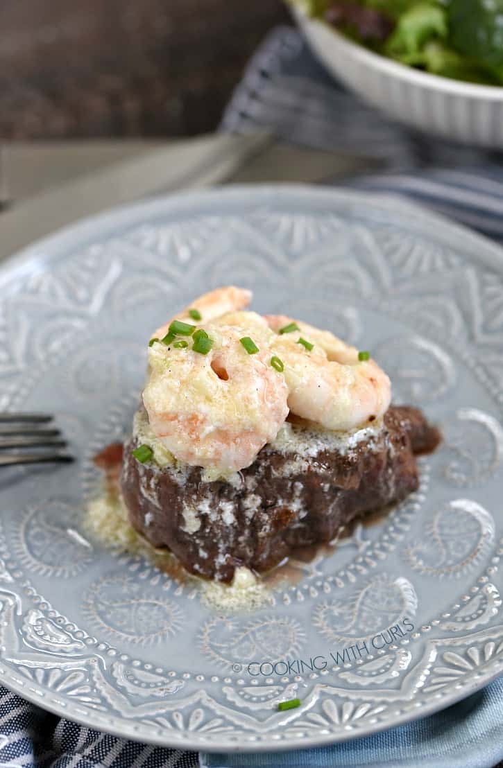 shrimp topped filet sitting on a gray plate