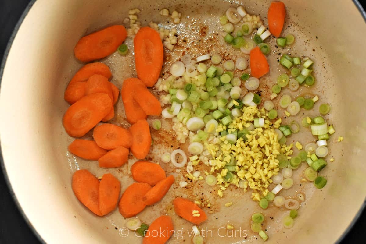 Sliced carrots, and onion, minced garlic and ginger in a pot. 