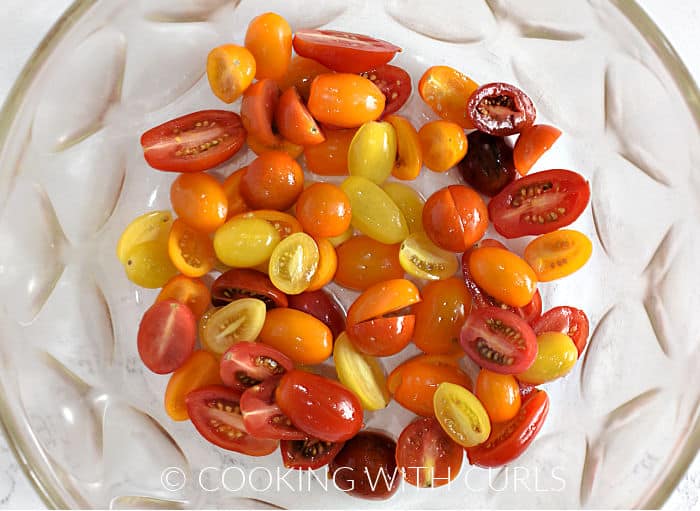 Sliced cherry tomatoes in a large bowl with sea salt.
