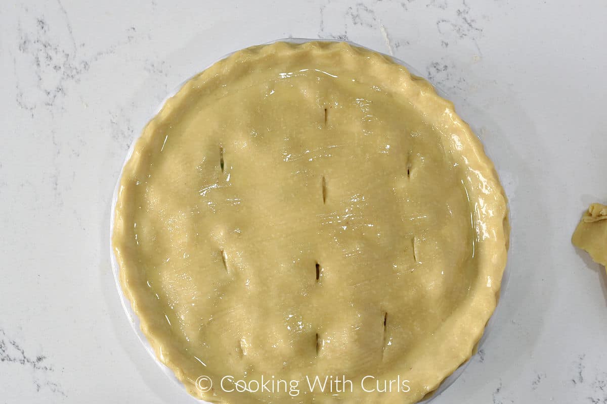 Looking down on a pie brushed with egg wash and 5 cuts into the top.