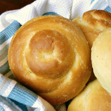 garlic dinner rolls pilled high in a blue striped napkin lined basket