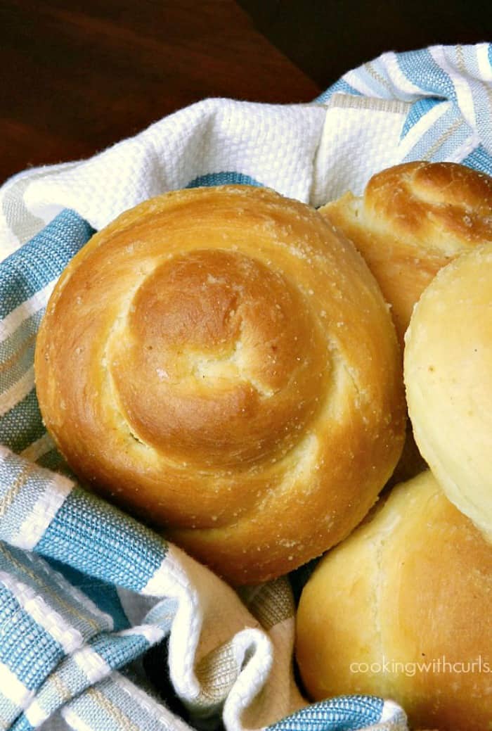 garlic dinner rolls pilled high in a blue striped napkin lined basket