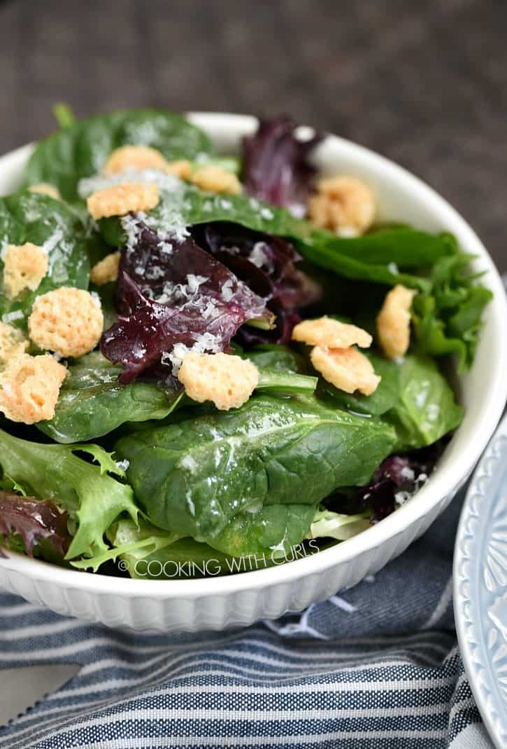Spring Mix Salad with citrus vinaigrette and parmesan crisps in a small white bowl