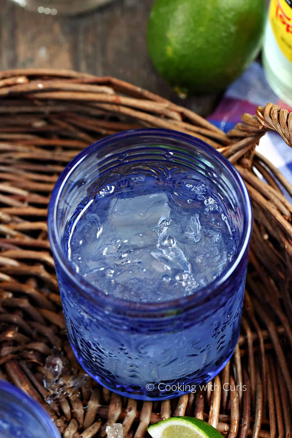 Tequila and lime juice over ice in a blue glass. 