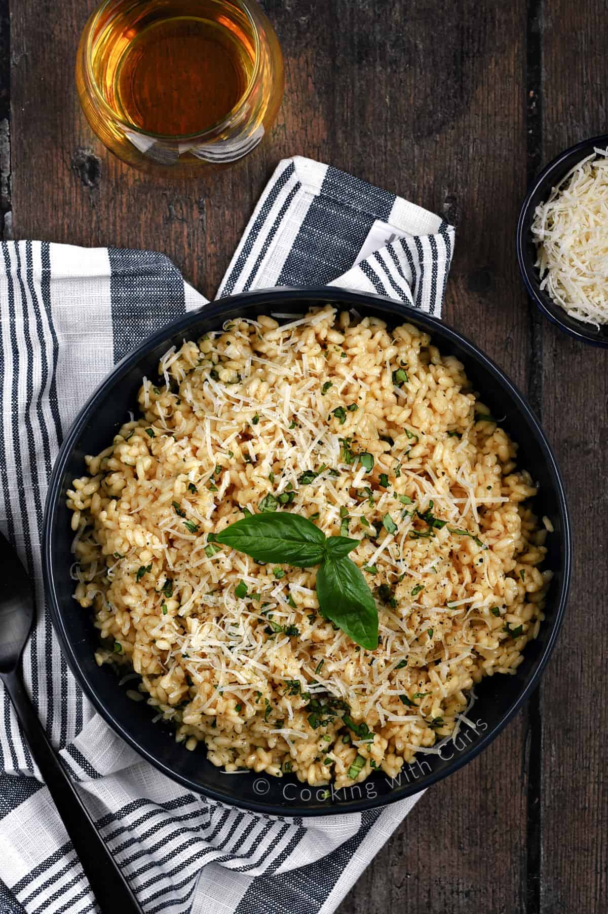 Looking down on a large bowl filled with basil risotto topped with grated parmesan cheese and fresh basil leaves.