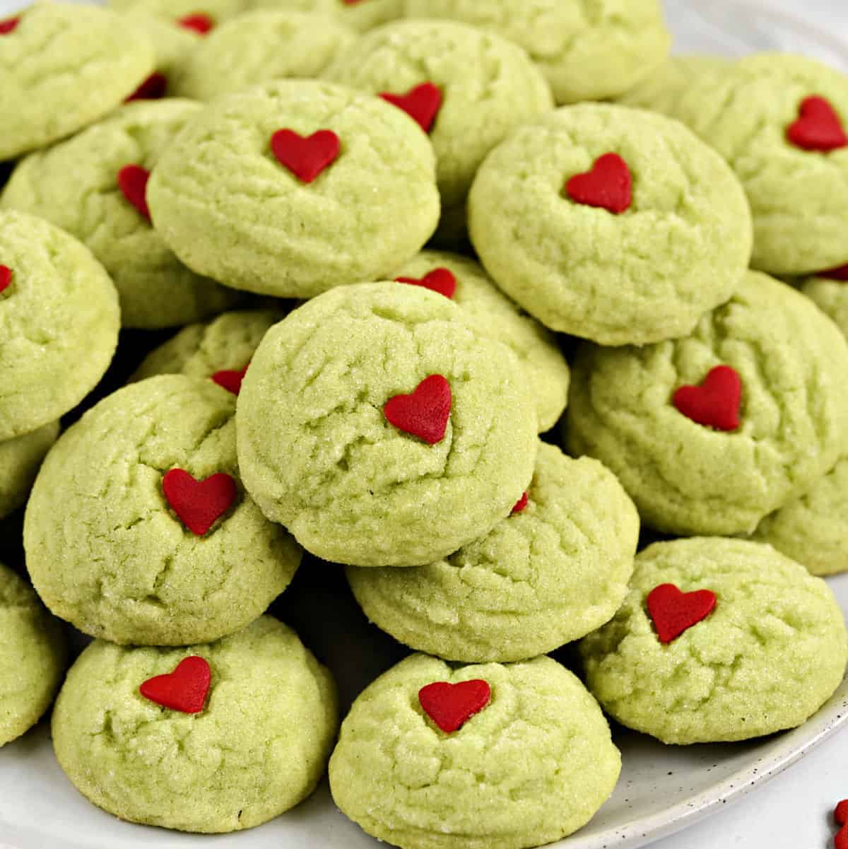 A plate filled with crinkly green sugar cookies with a small red heart in the center.