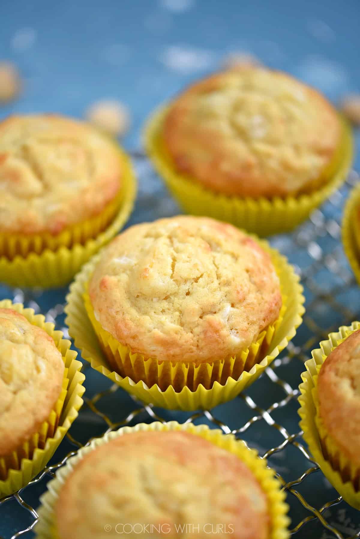 Pina Colada Muffins in yellow wrappers sitting on a wire rack.