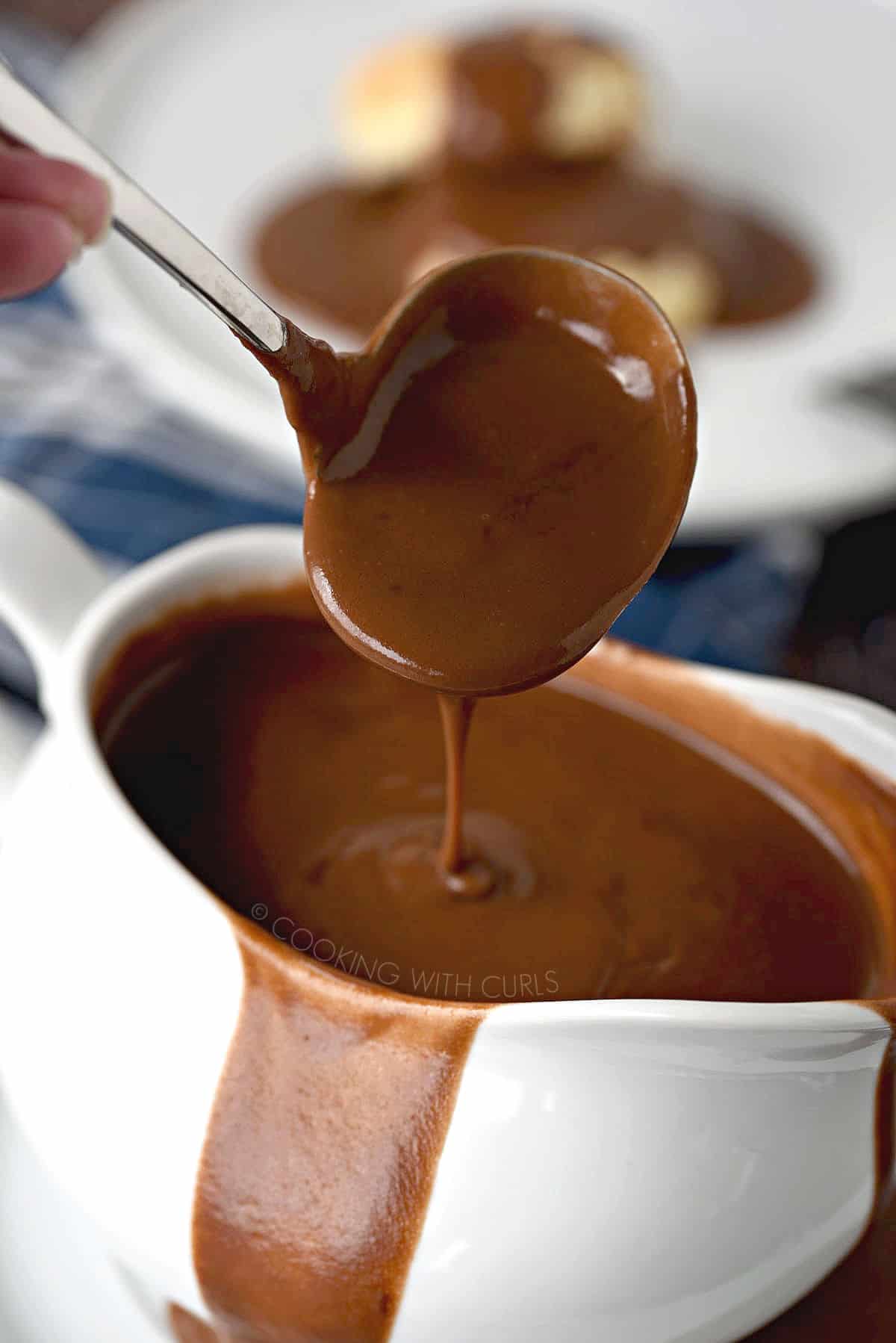 Thick, chocolate gravy dripping off the edge of a ladle into an overflowing gravy boat.