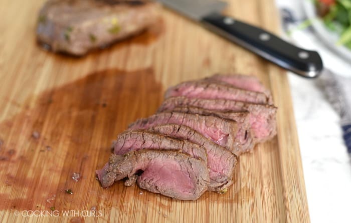 Thinly sliced steak on a wooden cutting board. 