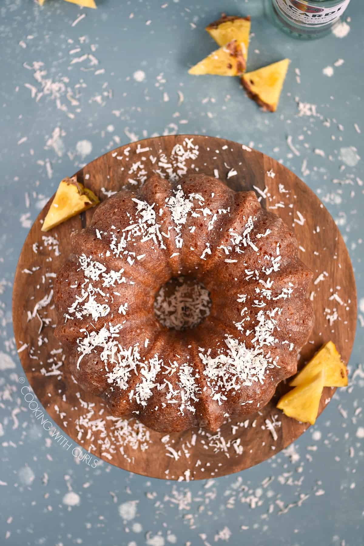 Looking down on a Bacardi Pina Colada Bundt Cake sitting on a wooden cake plate.