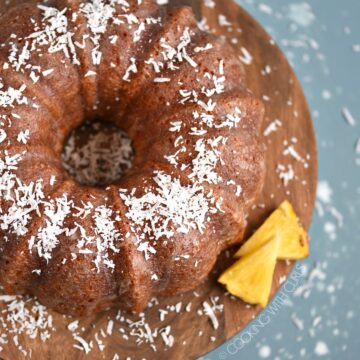 Looking down on a Bacardi Pina Colada Rum Cake sitting on a wooden cake plate.