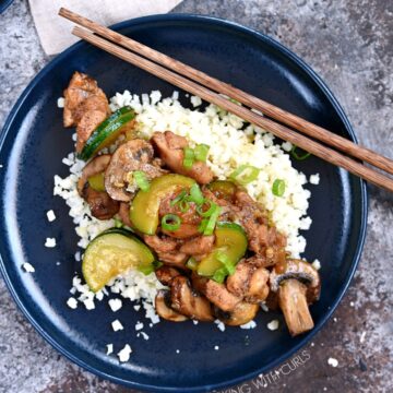 Instant Pot Chinese Garlic Chicken served over a bed of cauliflower rice, served on a blue plate with wooden chopsticks laying in the upper right hand corner of the plate