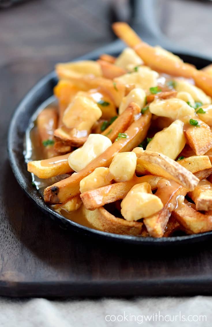 French fries and cheese curds topped with brown gravy in a cast iron skillet.