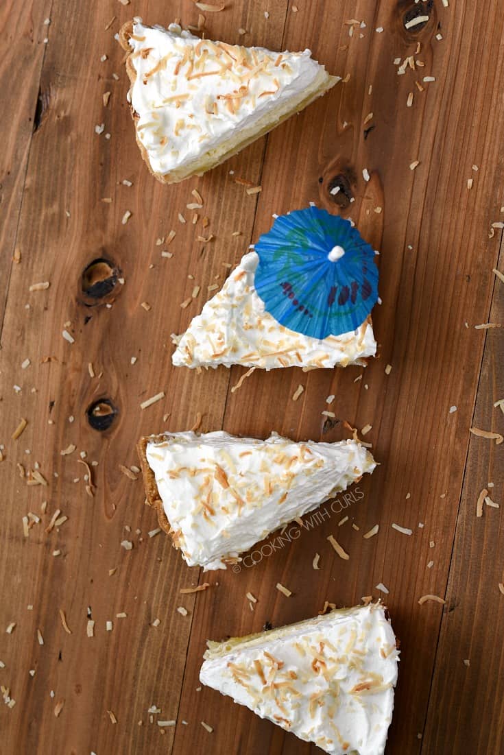 Overhead view of four slices of Pina Colada Pie, one slice with a blue cocktail umbrella