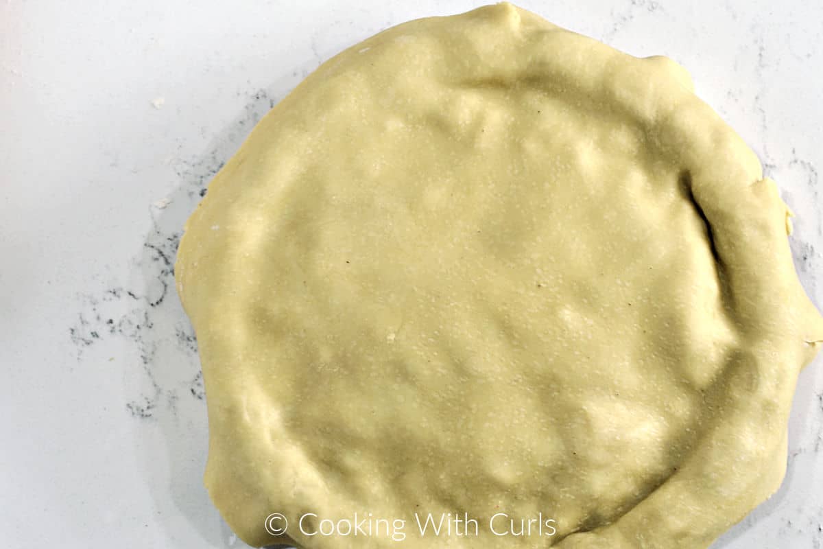 Top crust laying on top of a filled pie plate. 