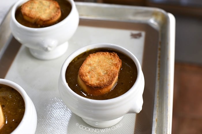 Three bowls of soup topped with a slice of toasted bread.