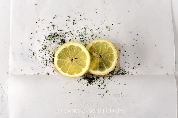 Two lemon slices on top of the seasoned cod filet.