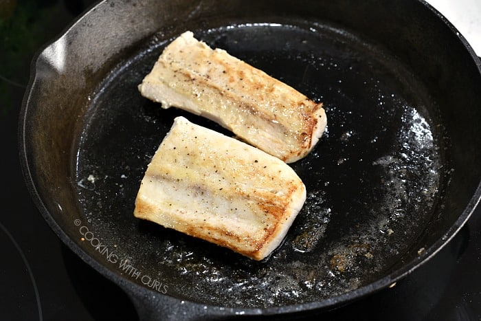 Two pan seared mahi mahi fillets in a cast iron skillet