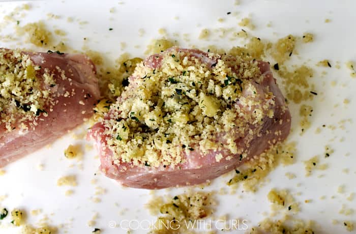 Two pork chops standing up on their side filled with stuffing. 