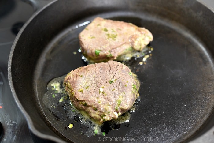 Two seared steaks in a cast iron skillet. 