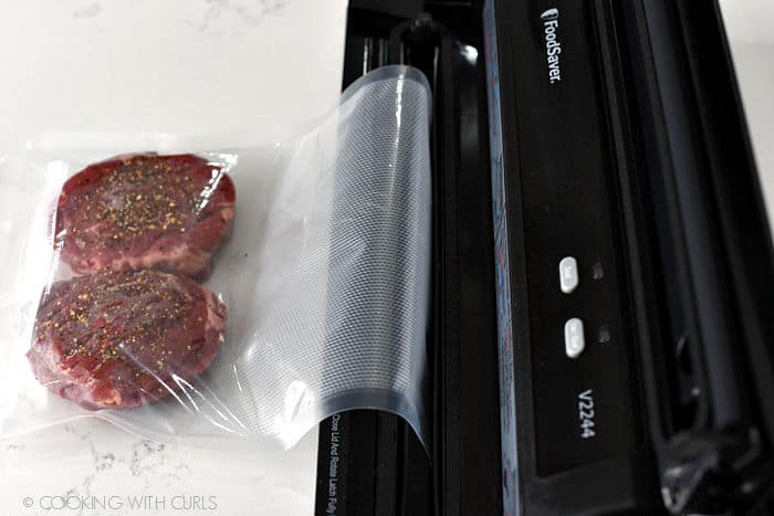 two seasoned filets in a vacuum bag with the end in the channel of a Foodsaver machine. 