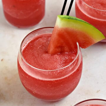 Three small glasses filled with frozen watermelon wine smoothie garnished with watermelon wedges.