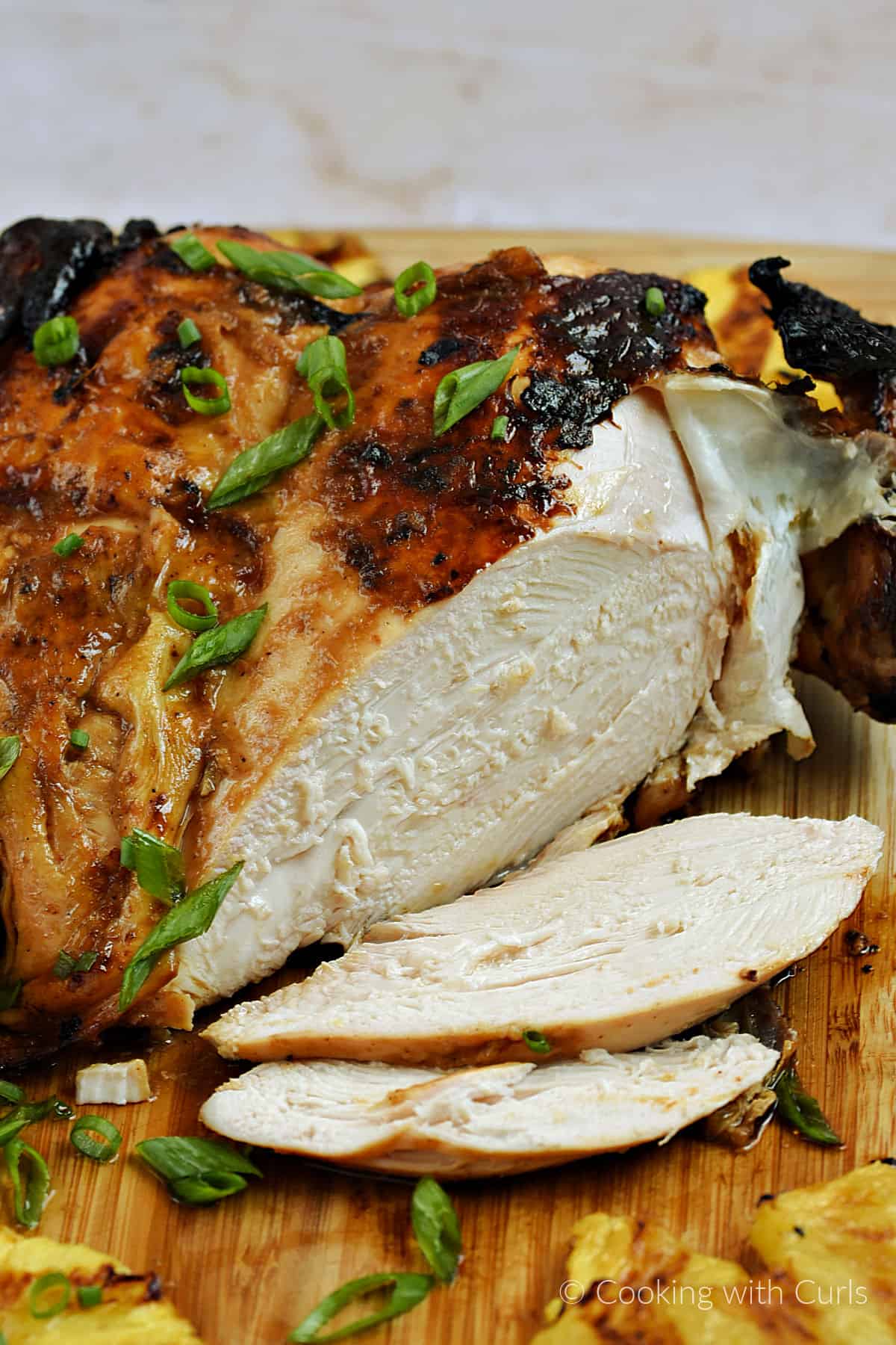 Whole chicken on a cutting board with two slices out of the breast. 