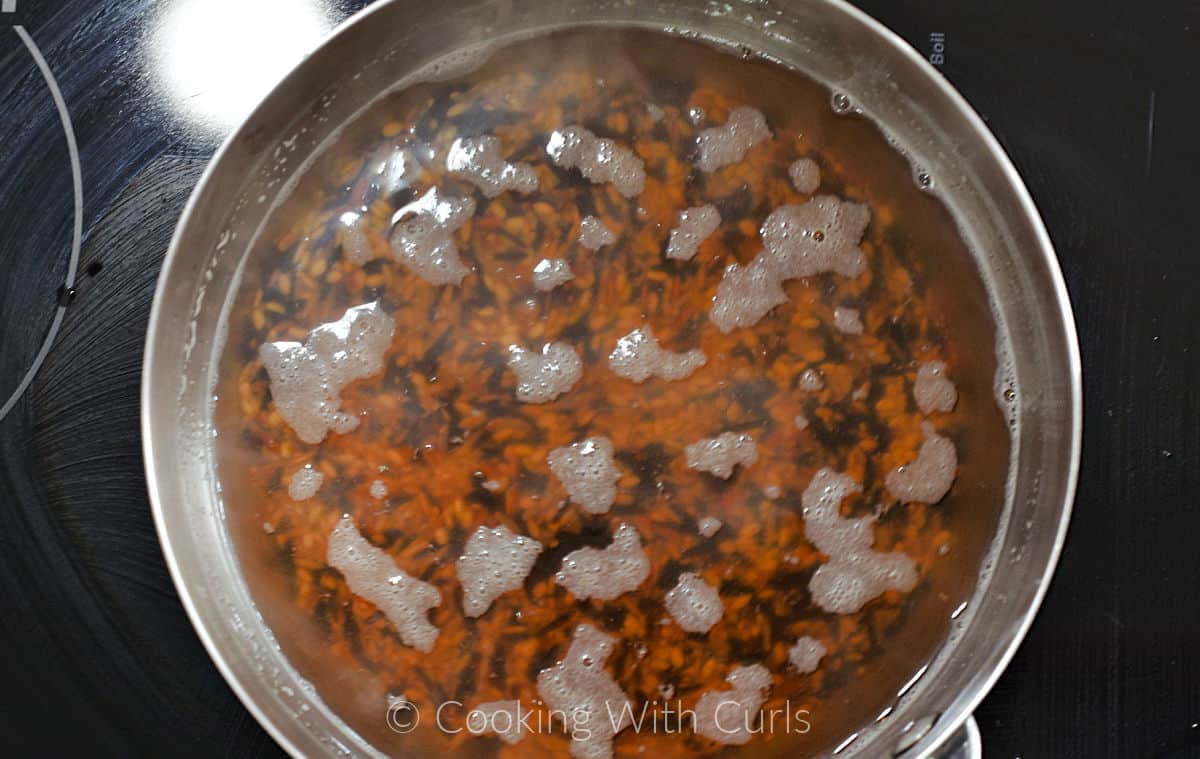 Wild rice and vegetable stock in a saucepan. 