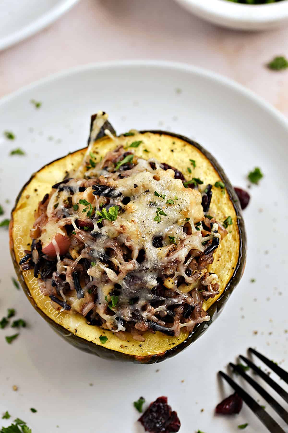 Wild Rice Stuffed Acorn Squash with apples, turkey, and cranberries on a plate.