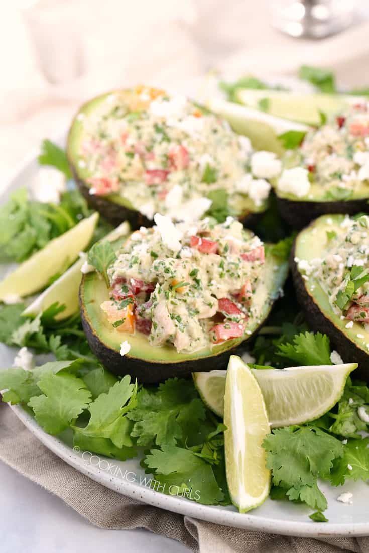 Healthy Tuna Stuffed Avocado halves sitting on a cilantro covered plate